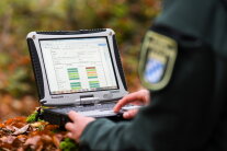 Förster arbeitet im Wald an einem Toughbook