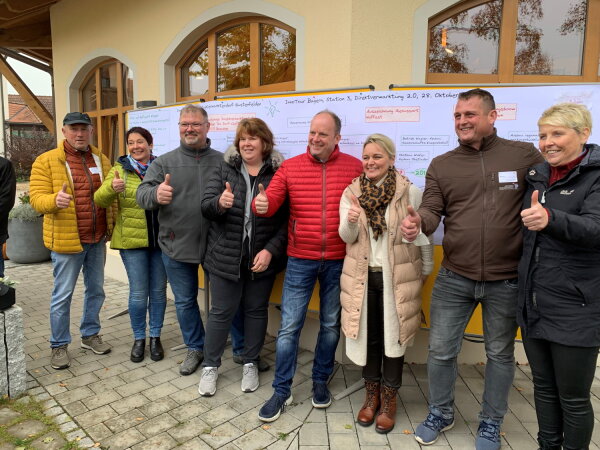 Die vier Gustenfeldener Familien vor der Infowand mit der zeitlichen Entwicklung der Direktvermarktung.