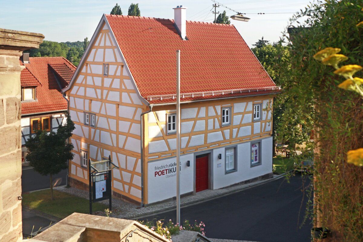 Blick von oben auf saniertes Fachwerkhaus mit rot gedecktem Satteldach und gelbem Fachwerk