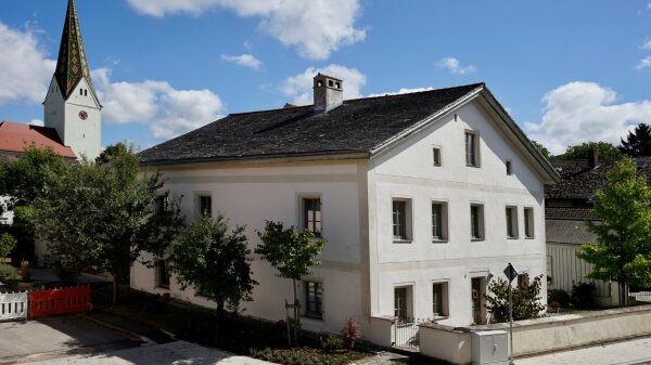 Ein weißes Gebäude und ein Kirchturm im Hintergrund.