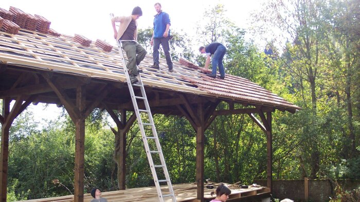 Menschen bebauen den Dach einer Hütte