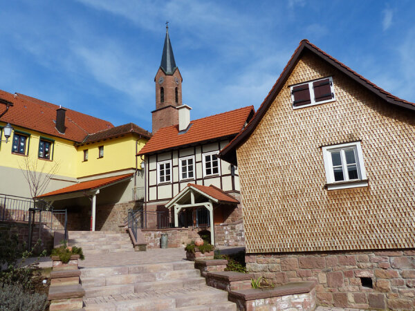 Ein neuer Dorfplatz mit einer Steintreppe. Im Hintergrund sieht man eine Kirche.