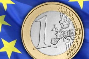 Eine Euromünze, im Hintergrund die blaue EU-Flagge 