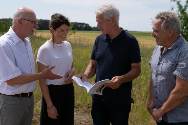 Projektleiterin und Bürger schauen auf dem Feld gemeinsam in die Projektmappe