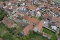 Luftaufnahme eines Dorfes mit alter Hofanlage im Vordergrund