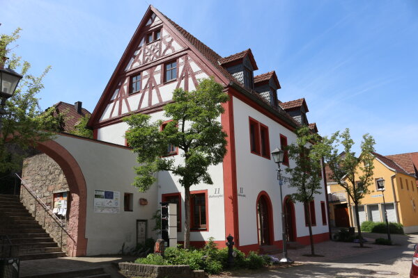 Historisches Fachwerkhaus in Bestzustand. Weiße Fassade, rotbraune Rahmung um Bögen und Fenster. 