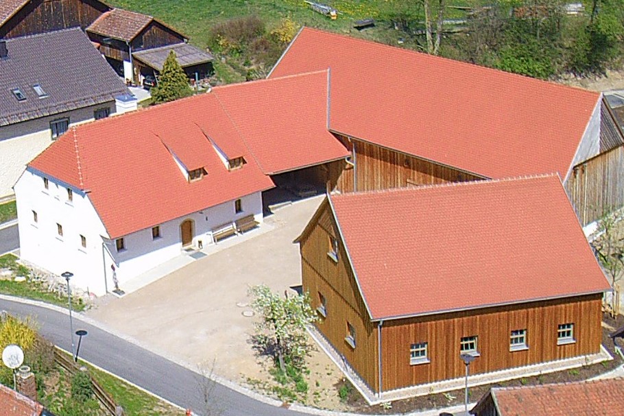 Eine Luftaufnahme zeigt den sanierten Dreiseithof neben der Dorfkirche.