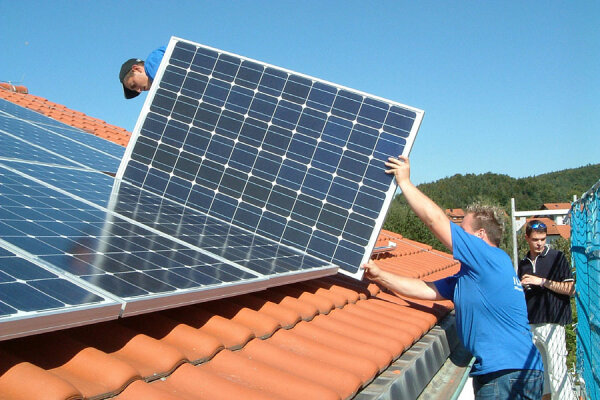 Arbeiter beim Verlegen von Photovoltaikelementen auf einer Dachfläche