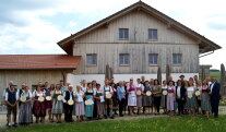 Alle Gewinner des Goldenen Gockels posieren für ein Gruppenfoto mit Ministerin Michaela Kaniber vor einem Haus. 
