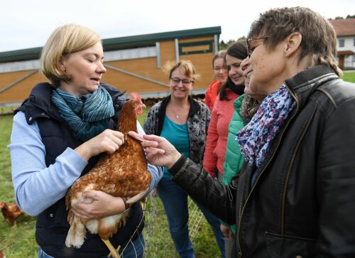 Bäuerin mit Huhn auf dem Arm im Gespräch mit einer Frauengruppe