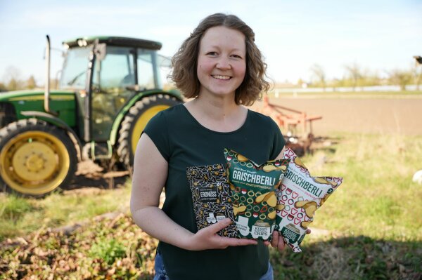 Eva Zwingel auf einem Feld mit Kartoffelchips-Tüten in der Hand.