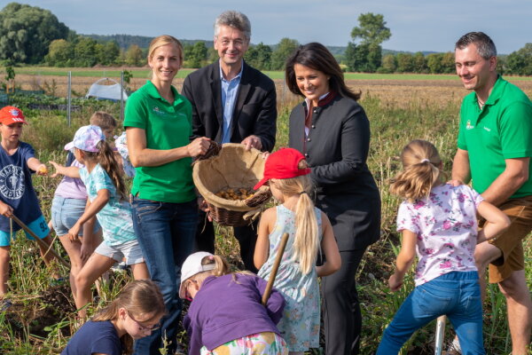 Landwirtschaftsministerin Michaela Kaniber und Kultusminister Prof. Dr. Michael Piazolo auf einem Kartoffelfeld mit Kindern und dem Landwirtspaar.