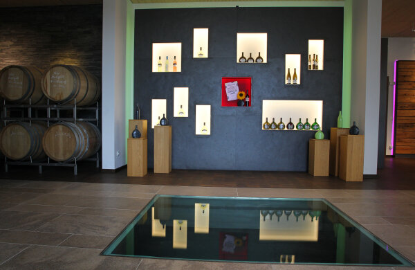 Ausstellungsraum einer Vinothek mit Weinfässern und unterschiedlichen Flaschen