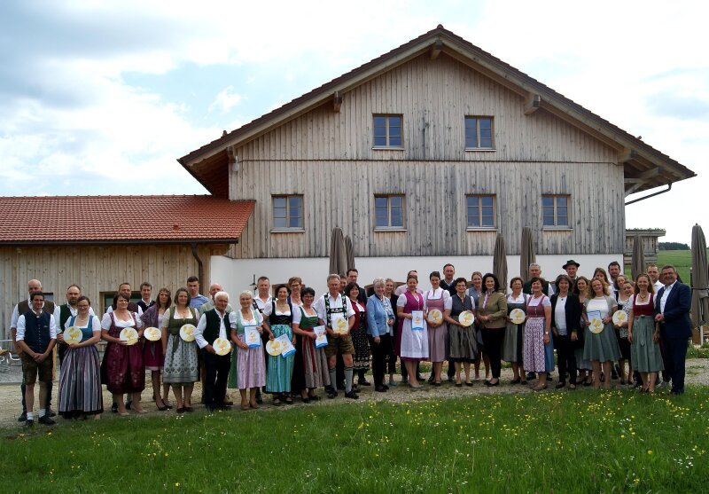 Mehrere Personen vor einem großen Haus mit Holzverschalung