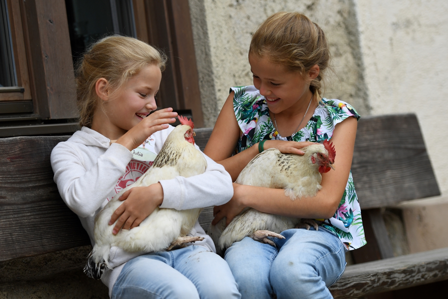 Zwei Mädchen halten Hühner in den Armen