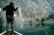 Fischer im Boot auf einem See beim Auslegen der Netze