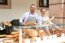 Eine Frau und ein Mann an einem Brotstand, wo sie ihre Produkte verkaufen.