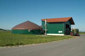 Biogasanlage an einem Feldrand, daneben Traktor