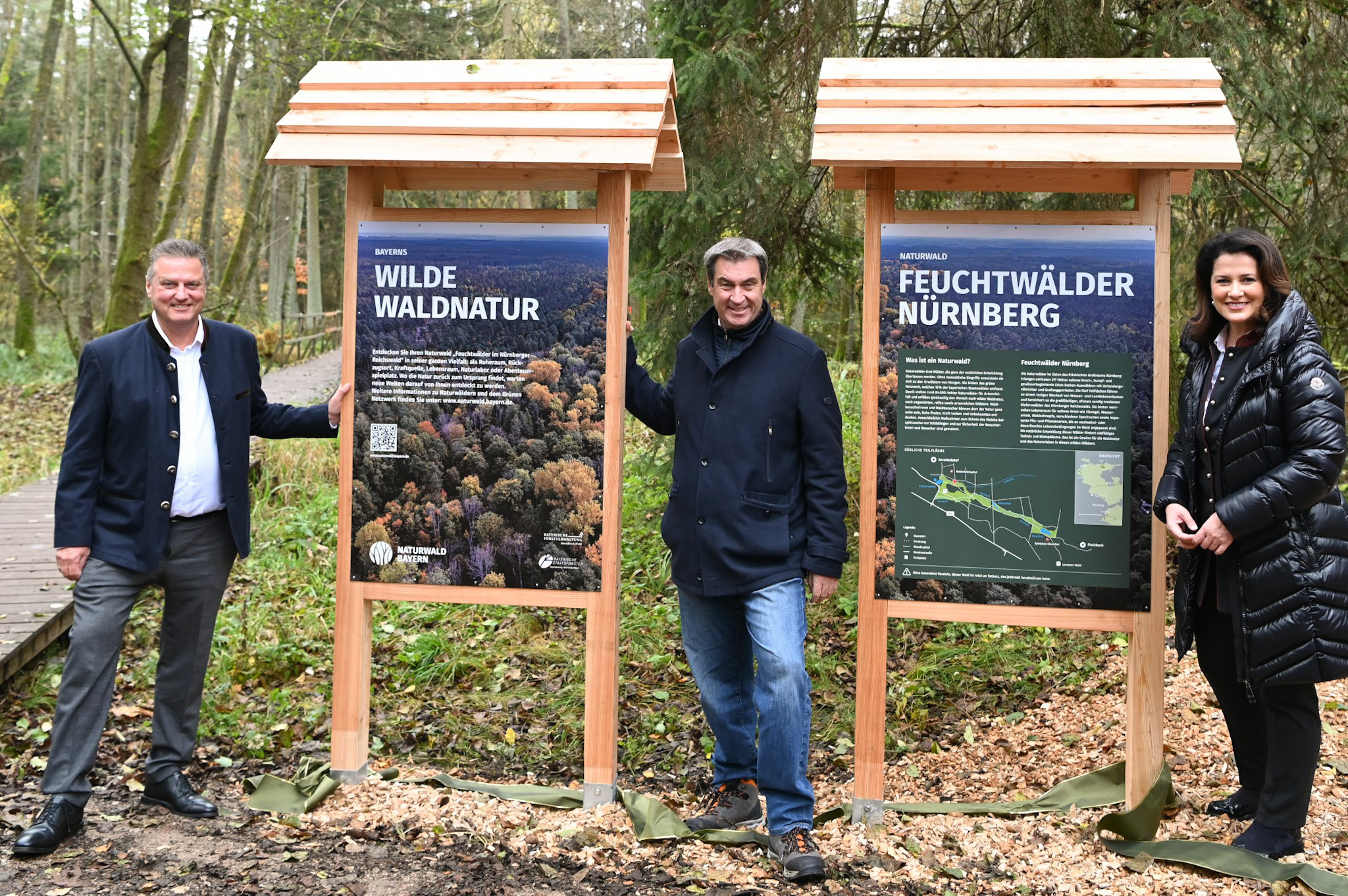 Ministerpräsident Söder mit Forstministerin Kaniber und Vorstandsvorsitzenden der Bayerischen Staatsforsten Martin Neumayer stehen an zwei Schilder zum Naturwald 