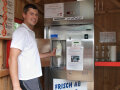 Ein junger Mann mit einer Milchflasche an einem Automat
