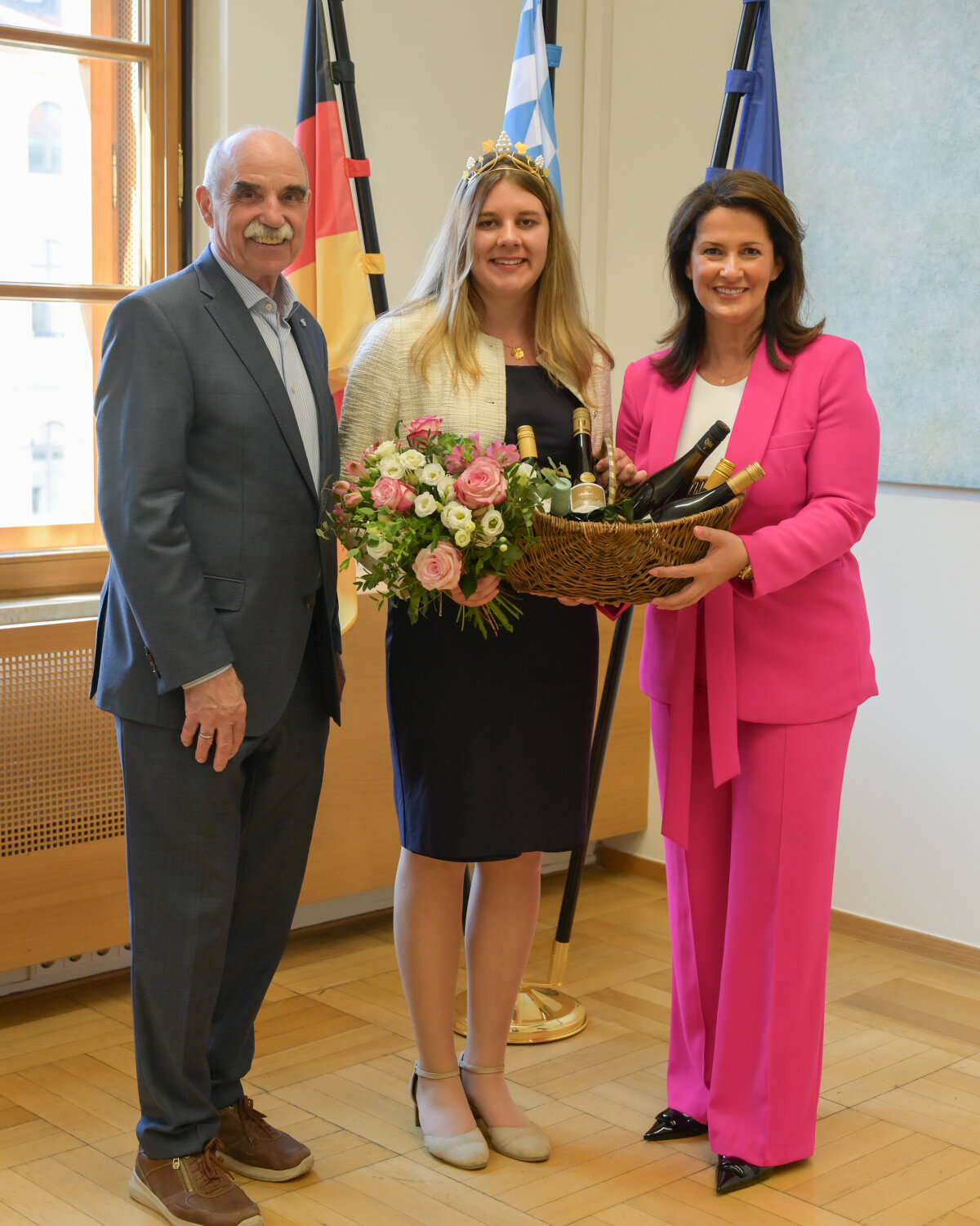 Das Bild zeigt die Staatsministerin in einem Raum des Ministeriums gemeinsam mit der Weinkönigin sowie dem Präsidenten des Fränkischen Weinbauernverbands.