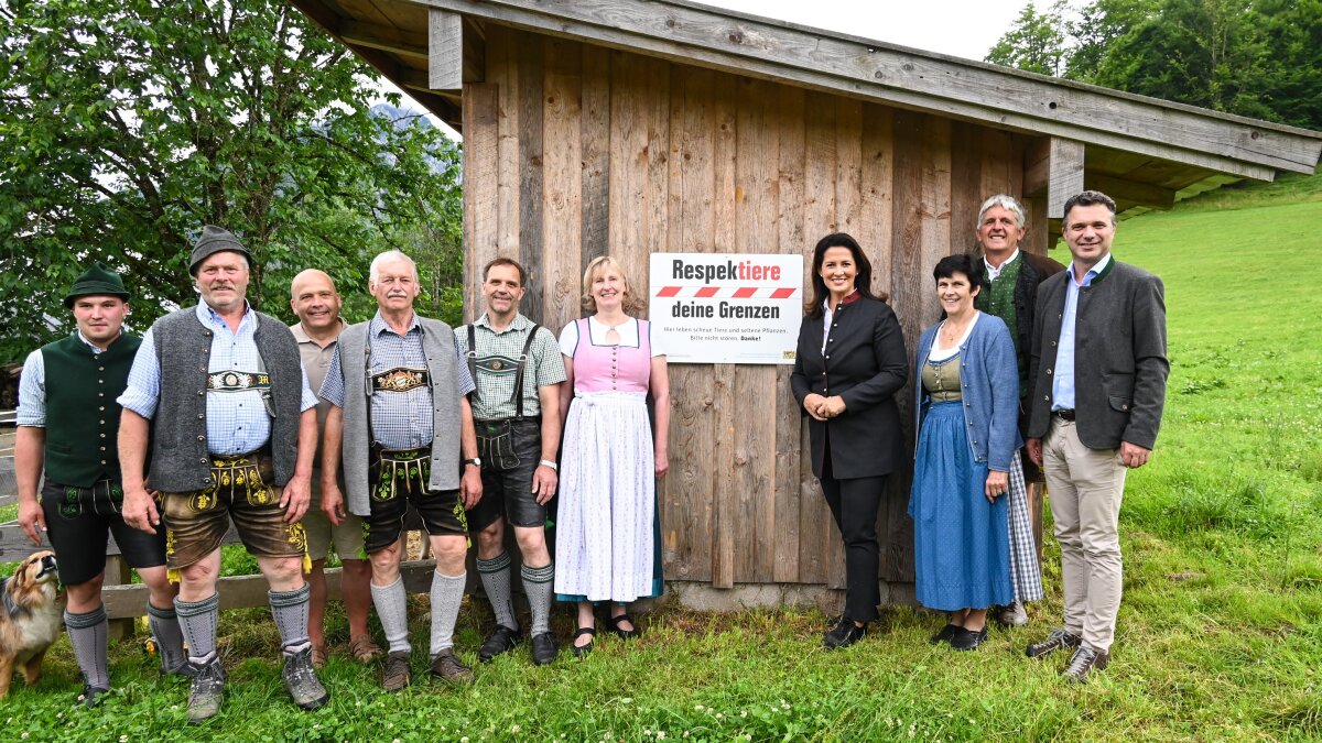 Ministerin Michaela Kaniber mit örtlichen Vertretern und Landwirten vor einem Stadel mit dem Schild der Initiative "Respektiere deine Grenzen"