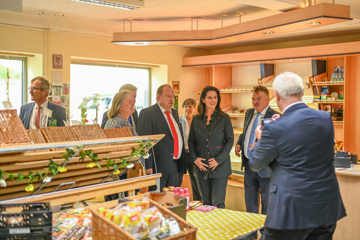 Das Bild zeigt Staatsministerin Kaniber im Gespräch mit mehreren Personen in einem Dorfgemeinschaftshaus in Grafengehaig.