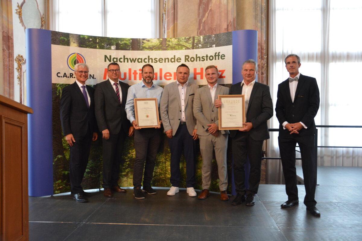 Das Bild zeigt die Preisträger. Zwei von ihnen halten Urkunden in der Hand.