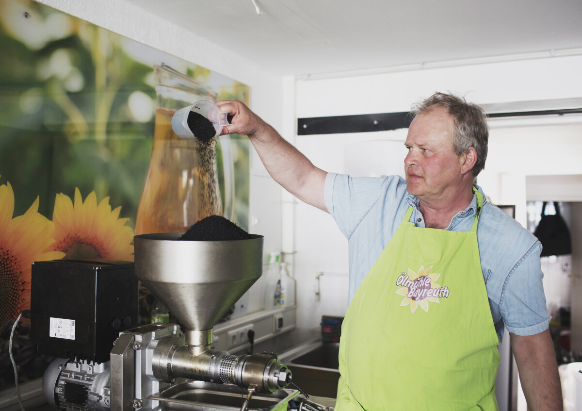 Das Foto zeigt Klaus Lünsmann aus der Öko-Modellregion Fränkische Schweiz beim Befüllen der geförderten Ölpresse mit heimischem Bio-Raps.