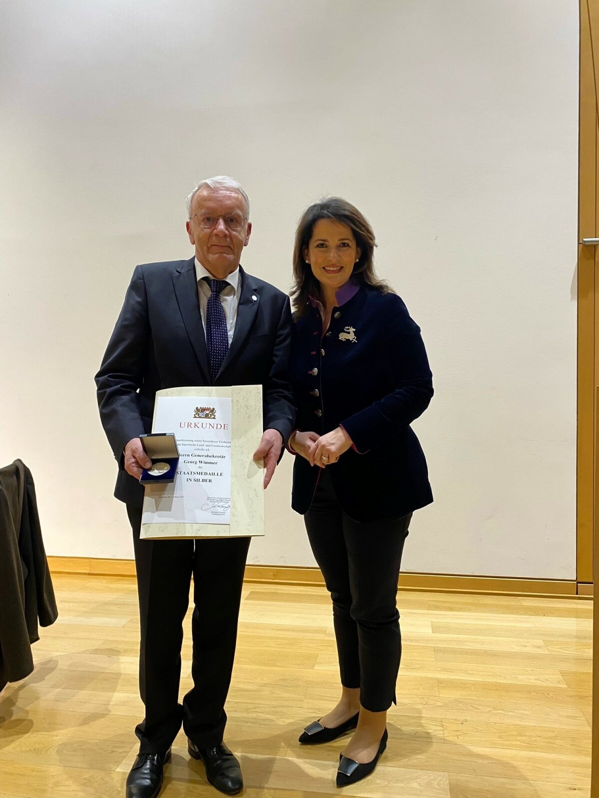 Staatsministerin Kaniber steht neben Bauernverbands-Generalsekretär Wimmer, der die Staatsmedaille in Silber in der Hand hält