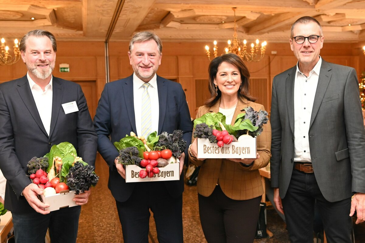 Staatsministerin Kaniber hält eine Kiste mit Gemüse in der Hand. Neben ihr stehen drei Vertreter der Fachgruppen Gemüsebau