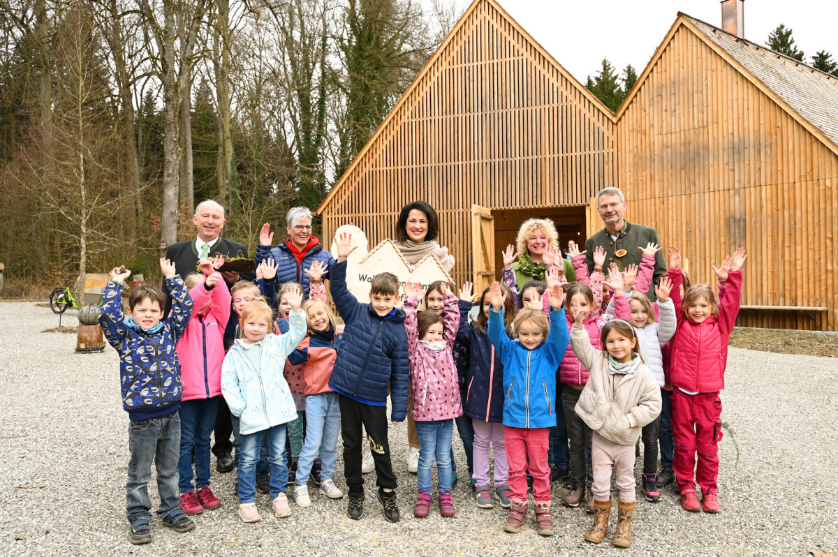 Forstministerin Michaela Kaniber (Mitte) gemeinsam mit Kindern des Evangelischen Kindergartens „Unterm Regenbogen“ Emmering vor dem neu gebauten Walderlebniszentrum.