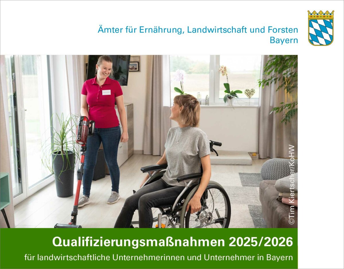 Eine Frau sitzt im Rollstuhl in einer Wohnung und lächelt einer anderen Frau zu, die neben ihr Staub saugt. 