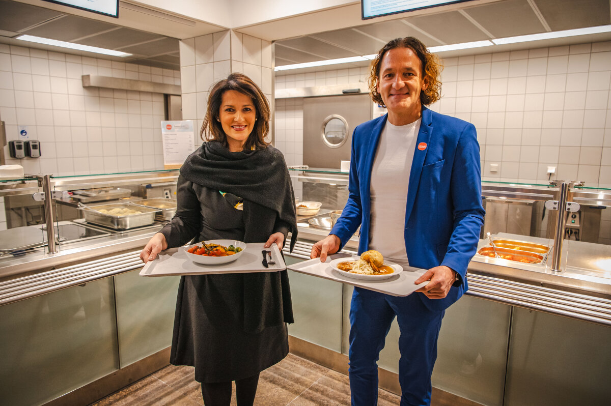 Ministerin Kaniber hält Tablet mit einer Gemüse-Bowl in der Hand. Neben ihr steht Martin Wild, CEO von Organic Garden Hospitality Partner GmBH