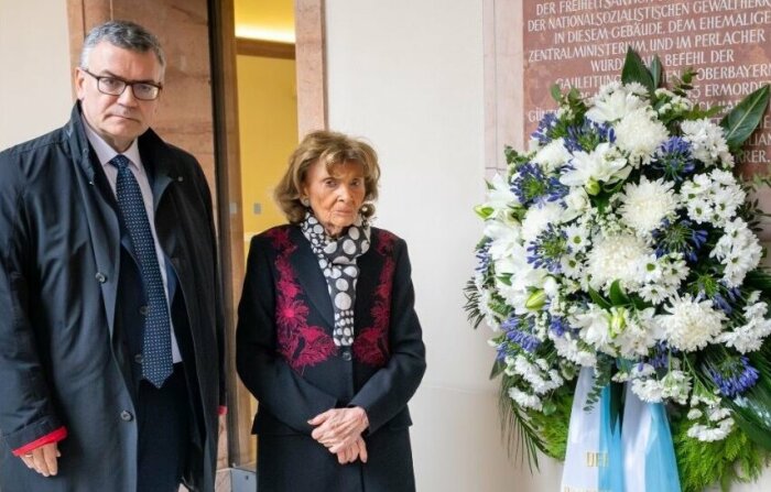 Dr. Florian Herrmann, Staatsminister für Bundesangelegenheiten und Medien und Charlotte Knobloch, Präsidentin der Israelitischen Kultusgemeine München und Oberbayern stehen bei der Gedenkfeier zum Ende des 2. Weltkriegs im Innenhof des Landwirtschaftsministeriums neben einem Trauerkranz.
