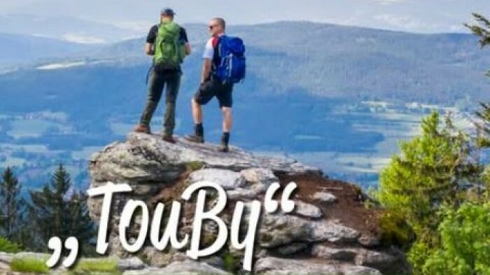 Zwei Wanderer stehen auf Felsen und betrachten das Bergpanorama