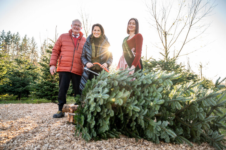 Forstministerin Michaela Kaniber und die Bayerische Christbaumkönigin, Sophia Adlberger stehen hinter einem frisch gefällten Christbaum