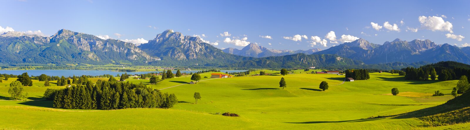 Landschaftsansicht mit Bergen und einem See im Hintergrund und Grasfläche im Vordergrund