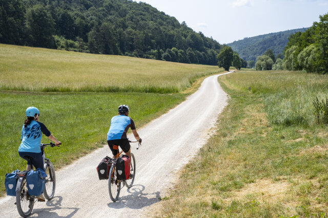 Zwei Personen fahren auf Fahrrädern auf einem Weg in der Natur.