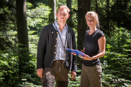 Ein junger Förster und einen junge Försterin mit Klemmbrett im Wald. (Foto: StMELF)