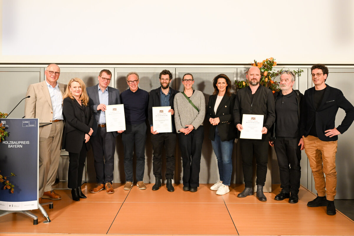 Gruppenfoto: (v. l.) Alexander Gumpp (proHolz Bayern), Prof. Lydia Haack (Juryvorsitzende), Anton Miller (B&O Wohnungswirtschaft GmbH), Prof. Hermann Kaufmann (HK Architekten, Hermann Kaufmann + Partner ZT GmbH), Matthias Kestel (Lehrstuhl für Entwerfen und Konstruieren der TUM),Enrica Ferrucci (Lehrstuhl für Entwerfen und Konstruieren der TUM), Staatsministerin Michaela Kaniber, Alen Jasarevic (jasarevic architekten bda dwb), Josef Zankl (Künstler), Benedikt Müller (jasarevic architekten bda dwb)