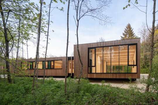 Holzgebäude mit großen Fensterfronten im Wald