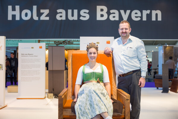 Waldkönigin Antonia Hegele sitzt auf einem Holzmöbel. Preisträger Gottfried Stettmer steht rechts daneben.