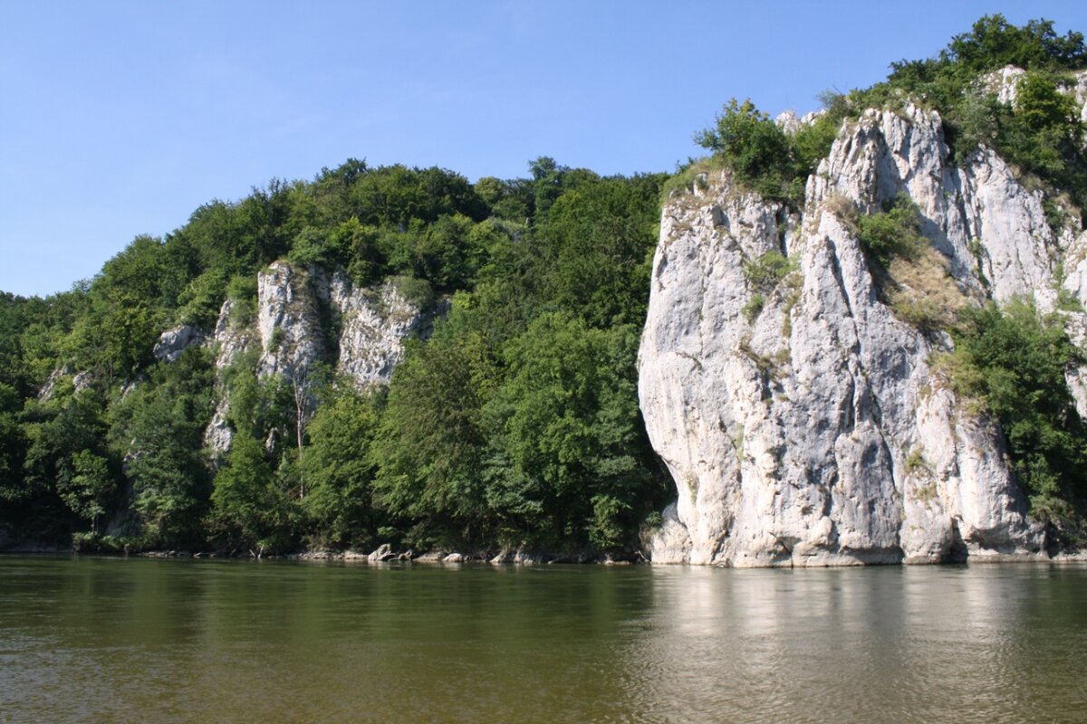 Riesige Felsfomationen mit Laubwald neben einem Fluss (© Felix Brundke)