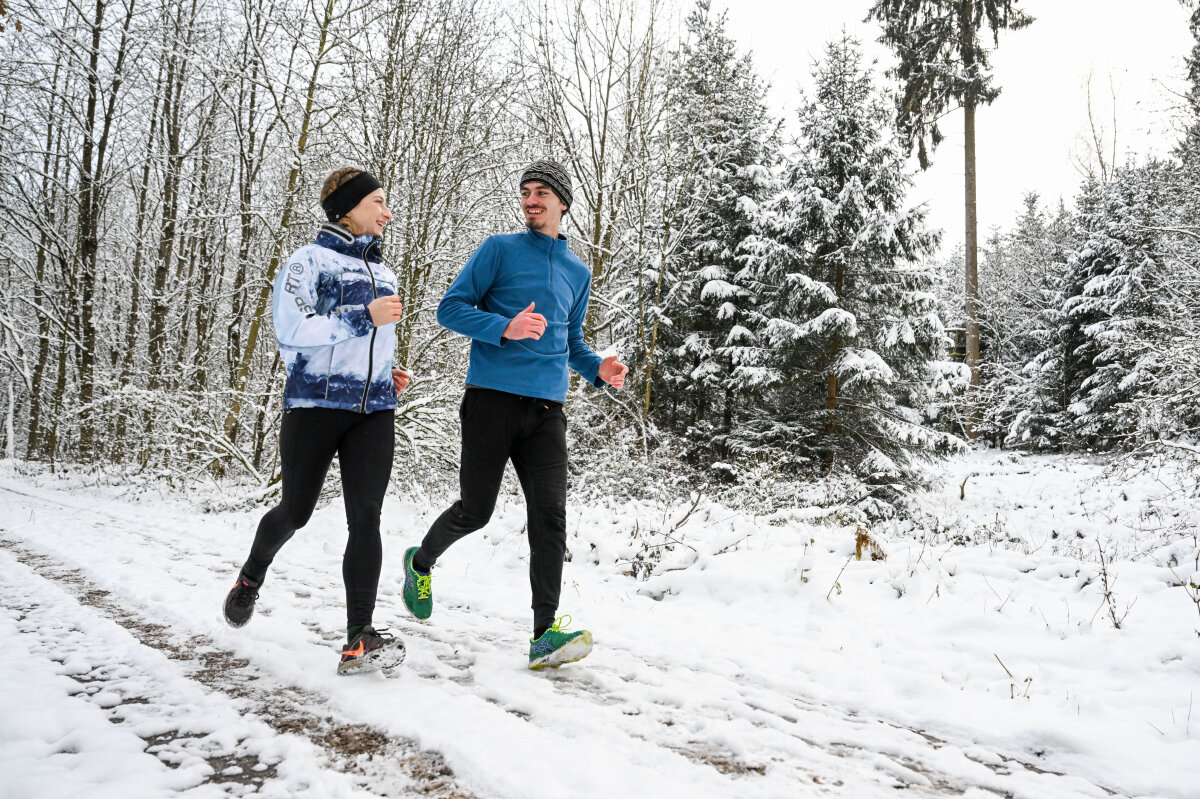 Joggerin und Jogger im tiefverschneiten Wald (© Tobias Hase)