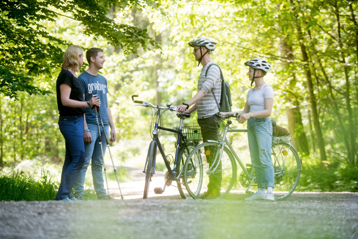 Zwei Spaziergänger unterhalten sich mit zwei Radfahrern im Wald