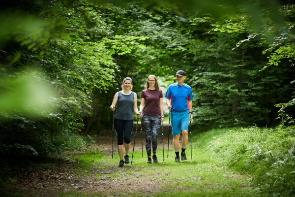 Zwei Frauen und ein Mann beim Nordic Walking im Wald
